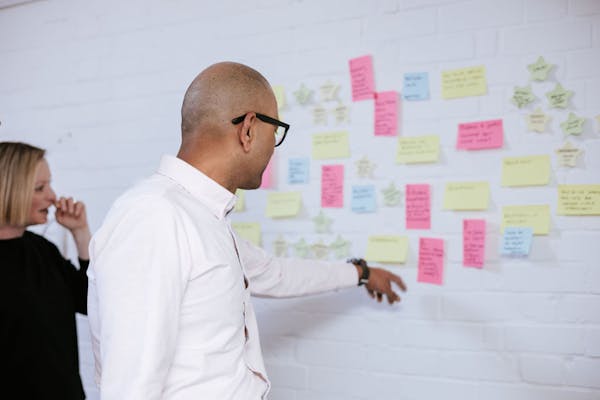 Thiscovery team collaborating with post-it notes on a wall.