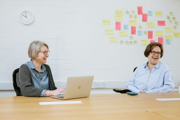 Members of the Thiscovery team laughing while collaborating in their office.